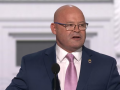 Screenshot of O'Brien, a white man in a suit, wearing a Teamsters lapel pin, speaking at the convention