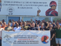 A group of workers hold a banner in front of a French banner. 