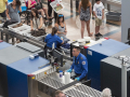 TSA workers are shown screening bags and scanning passengers at an airport