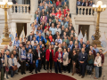 Fifty people pose on the stairs inside the Rhode Island capitol.