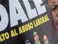 A man yells while holding a sign saying DALE ‘Alto Al Abuso Laboral’ (DALE stop workplace abuses)