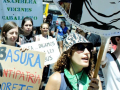 Several people with banners in Spanish march towards the camera’s right