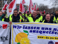 People with red flags march behind a banner adorned with lemons.