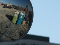 Two portajohns are reflected in a truck side mirror.