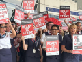 Dozens of men and women of various ethnicities wearing dark blue flight attendant uniforms hold signs saying “Ready to Strike”