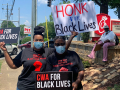 Two CWA members with signs for Black lives on the pavement