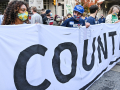 A group of people holds a large white banner with the slogan Count Every Vote.