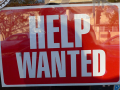 Help Wanted sign - background red, text white, in window of store