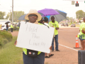 A woman holds a sign reading Hold the Line while others stand on the picket line.