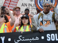 Members of the Laborers Union march during the May Day rally in New York City, behind a black banner that says solidarity in multiple languages, including Arabic.