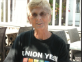 A smiling woman is pictured with short blond hair and a black Union Yes t-shirt with a rainbow on it.