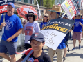 Actor Sam Humphrey and several others march towards the camera with ‘SAG AFTRA on strike’ and ‘Writers Guild of America On Strike’