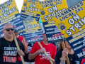 White and Black men and women march with picket signs that say "Teamsters Local 238, Marathon Petroleum Co, Unfair Labor Practices against Detroit refinery workers." Most of those whose T-shirts are visible are wearing messages like "Teamsters against Trump," "Trump is a scab," and "Harris-Walz" with an IBT local logo.