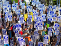 View from above of a sea of marchers outdoors, all carrying matching printed "UAW on strike" picket signs