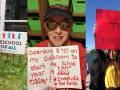 Three pictures: First one shows a happy child, hand in air, with Preschool for All yard sign; second shows a woman holding a handwritten sign: "Spending $787 on my classroom to start the school year is NOT okay! #InvestInEd #RedForEd"; third shows a young woman with a handwritten sign: "FAIR TAXES IS INVESTING IN US"