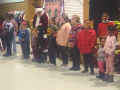 Kids stand in a row, with Santa among them, inside the union hall at a Christmas function