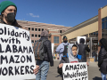 Adult and boy with signs in front of Whole Foods supporting Alabama Amazon workers attempting to unionize.