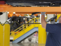 An autoworker tightens bolts on a car chassis above his head.